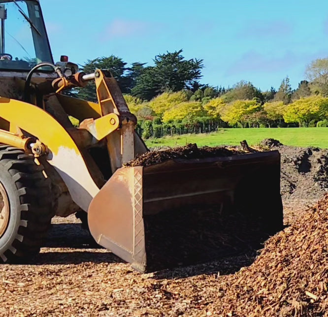 Loader shifting mulch in a paddock